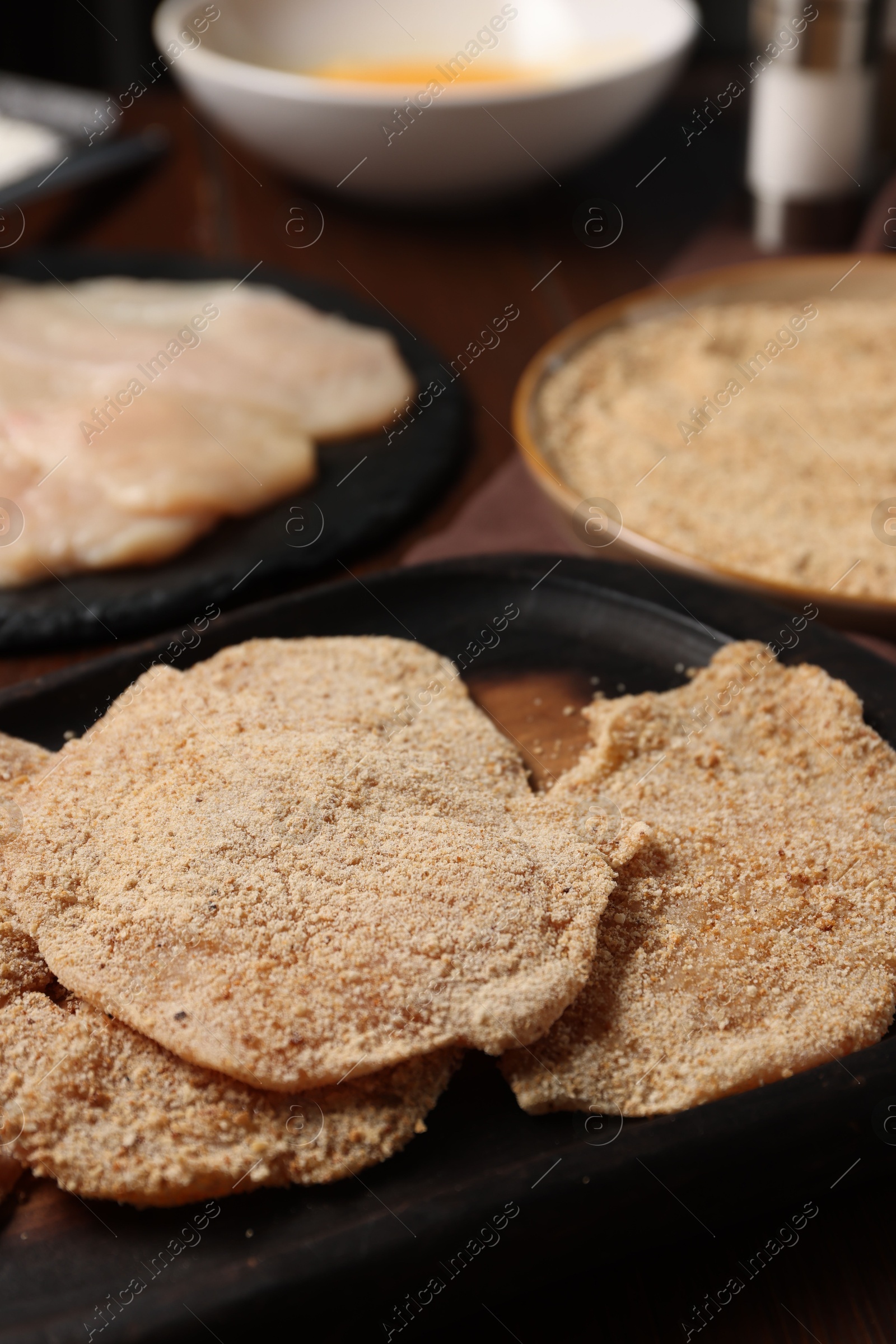 Photo of Making schnitzels. Raw meat and other ingredients on wooden table, closeup