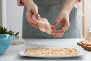 Photo of Woman making schnitzel at white table, closeup