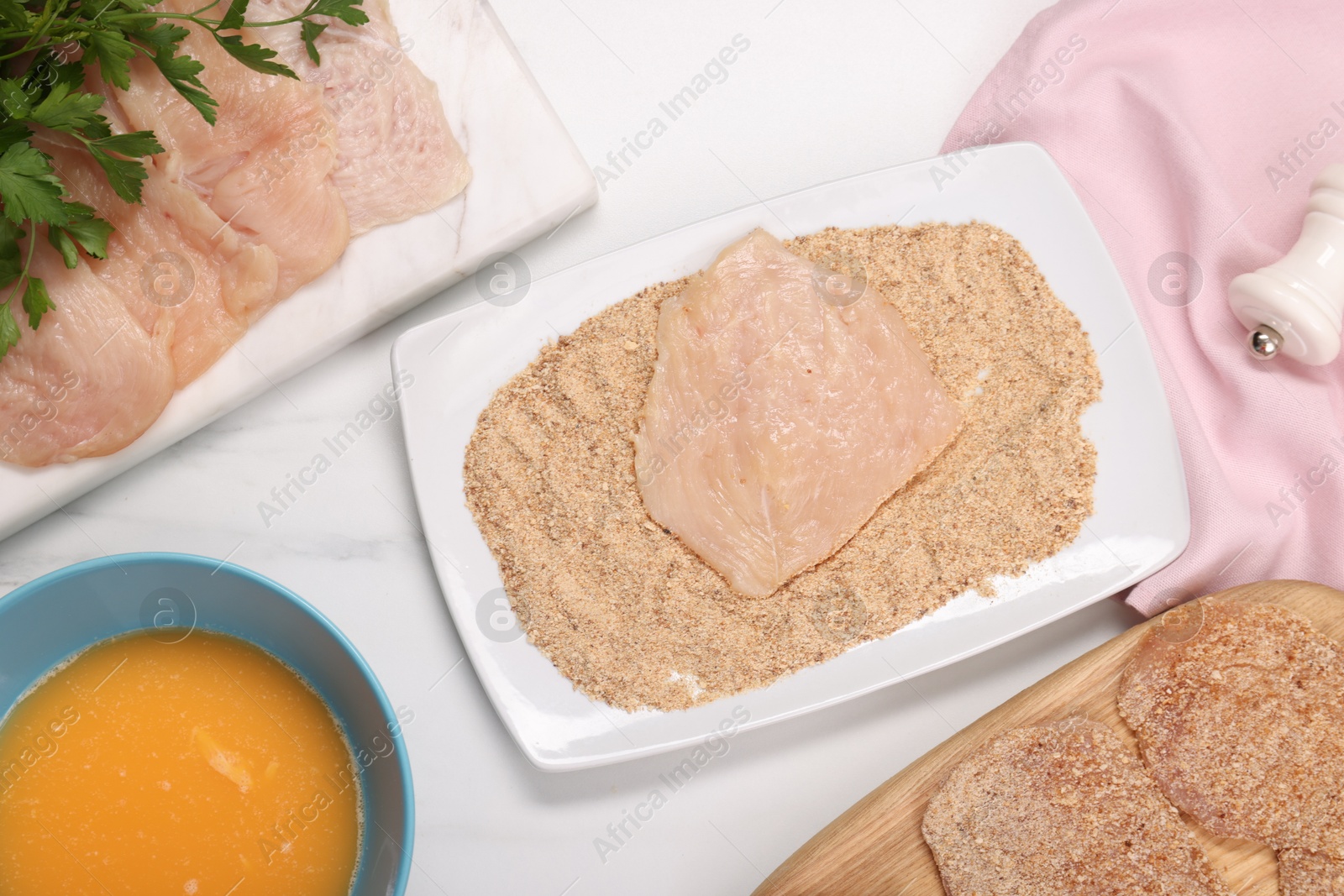 Photo of Making schnitzels. Raw meat and other ingredients on white marble table, flat lay