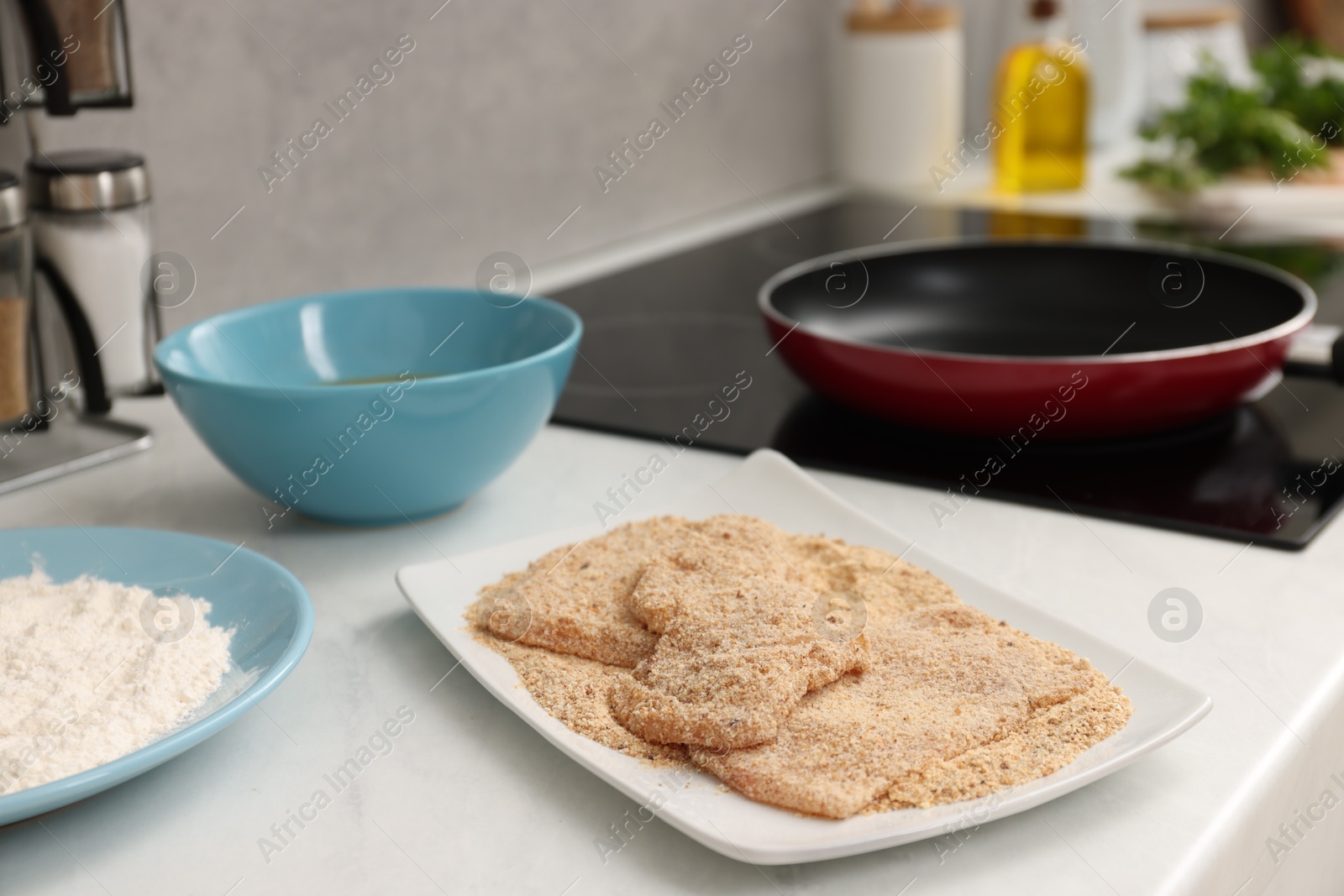 Photo of Making schnitzels. Raw meat with bread crumbs on white table