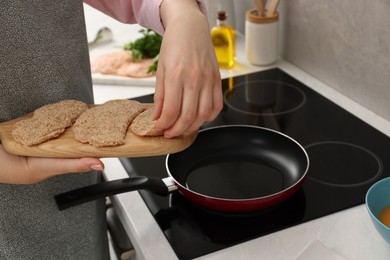 Photo of Woman cooking schnitzels in frying pan on stove, closeup