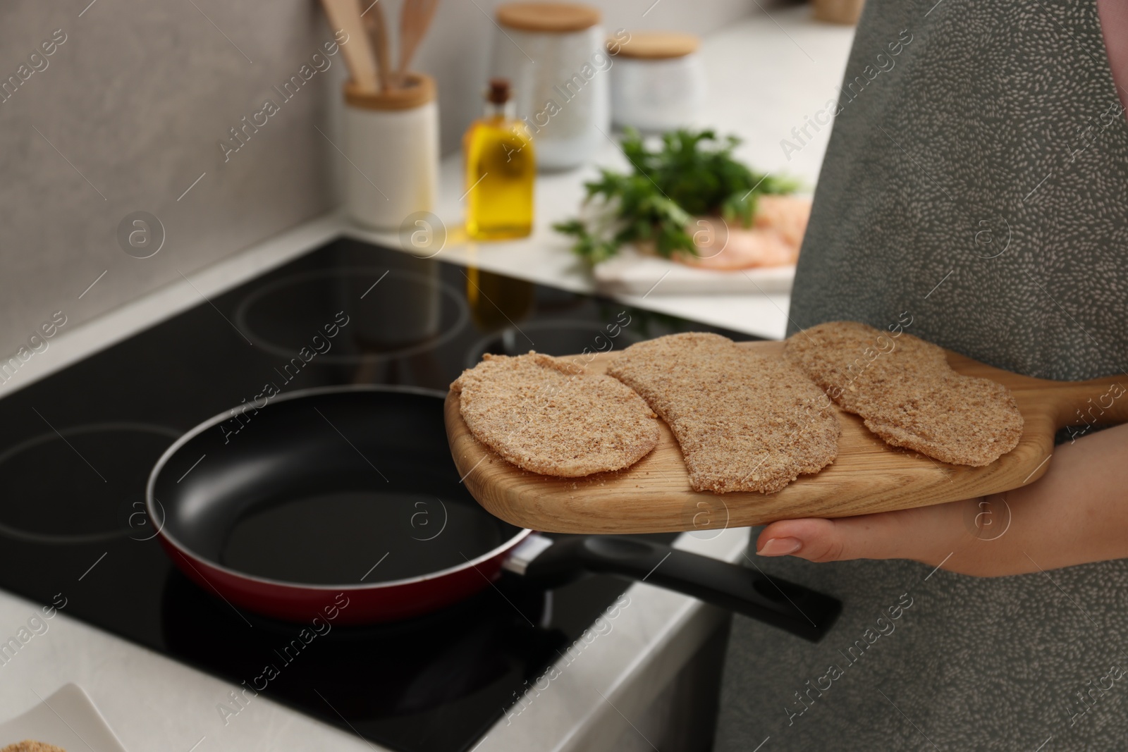 Photo of Woman cooking schnitzels in frying pan on stove, closeup