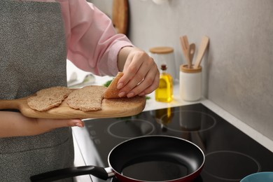 Woman cooking schnitzels in frying pan on stove, closeup