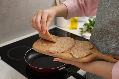 Woman cooking schnitzels in frying pan on stove, closeup