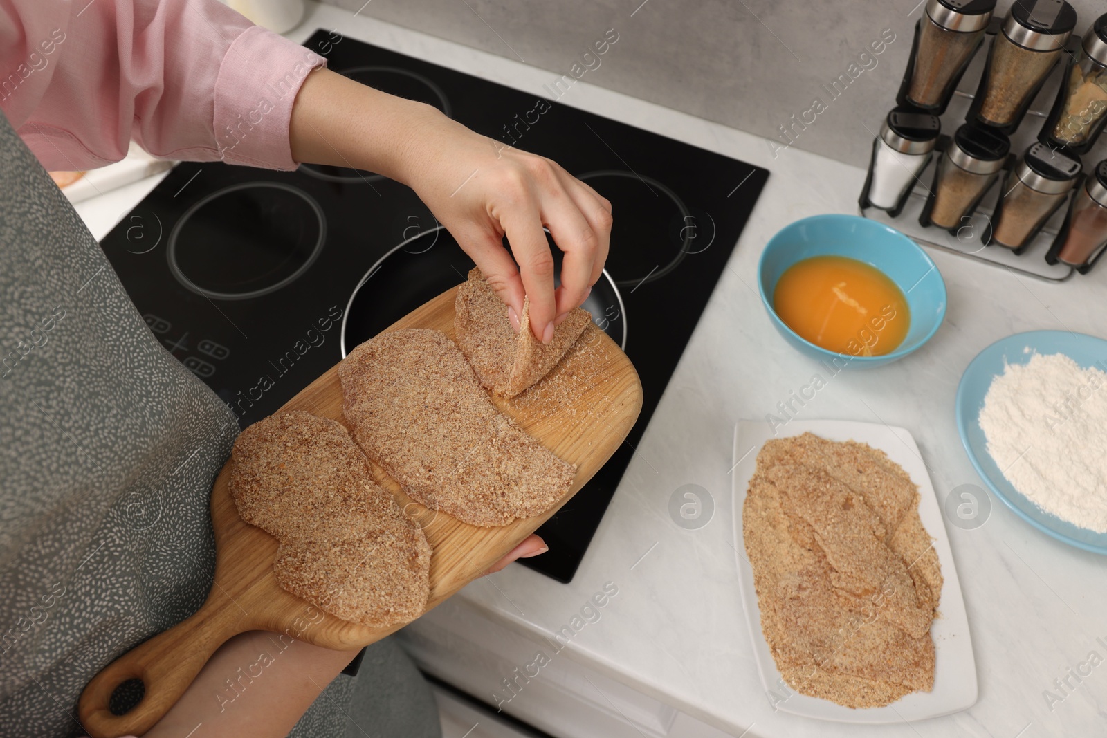 Photo of Woman cooking schnitzels in frying pan on stove, closeup