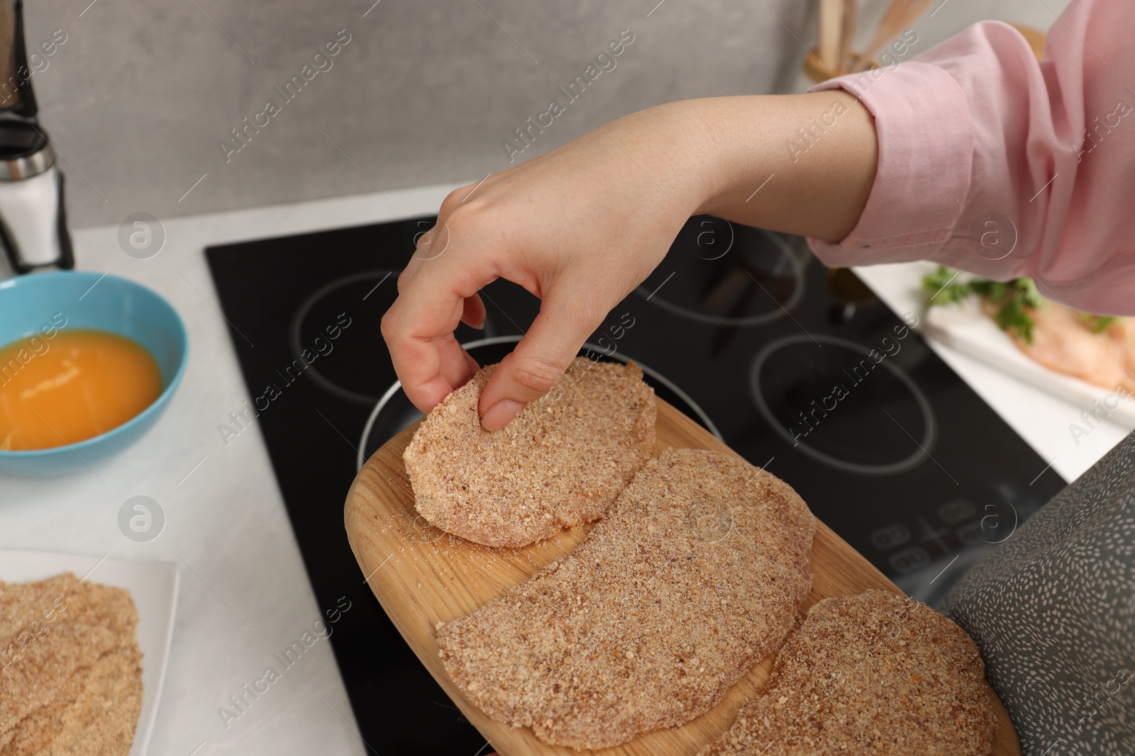 Photo of Woman cooking schnitzels in frying pan on stove, closeup