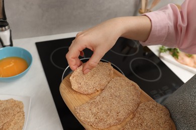 Photo of Woman cooking schnitzels in frying pan on stove, closeup