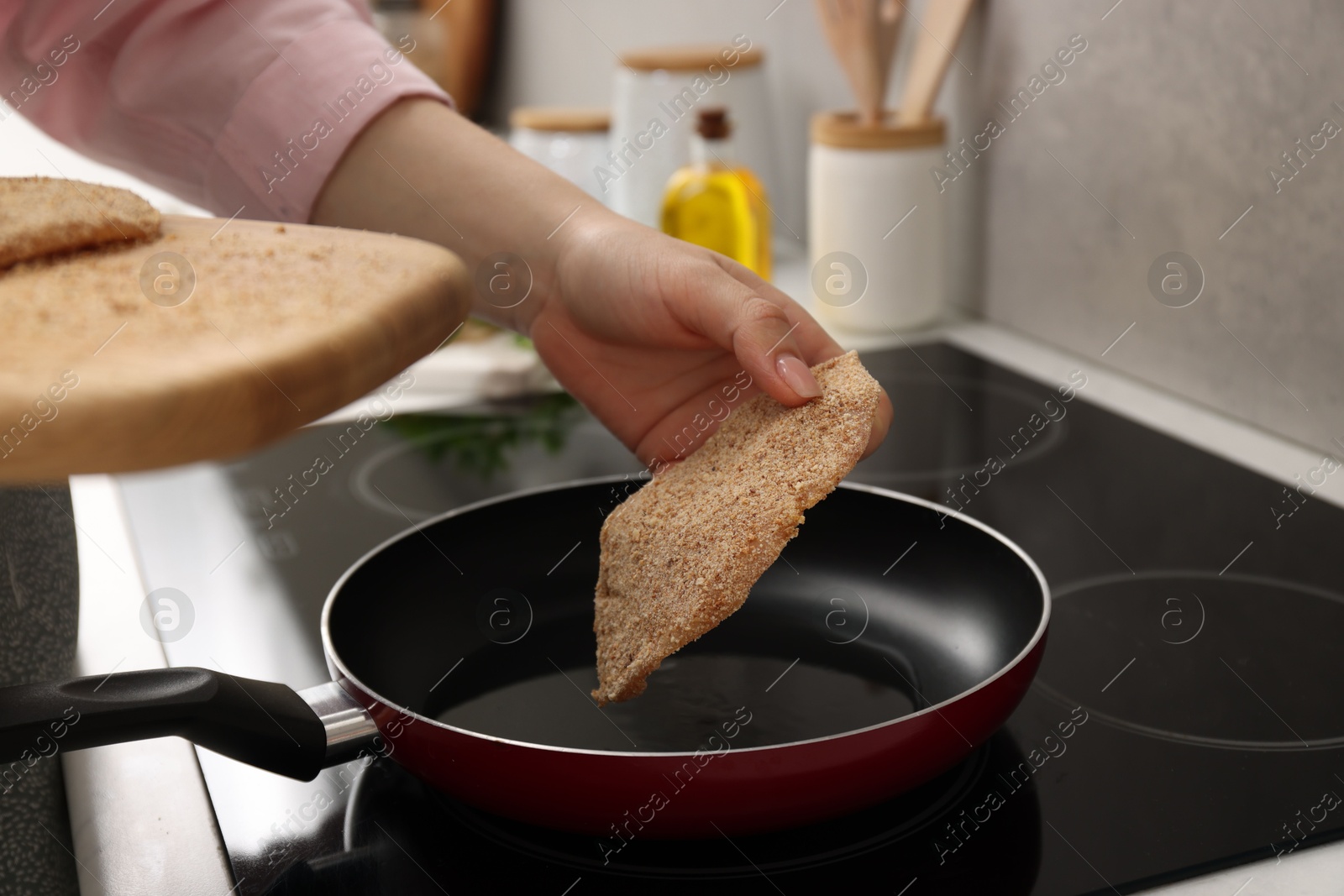 Photo of Woman cooking schnitzels in frying pan on stove, closeup