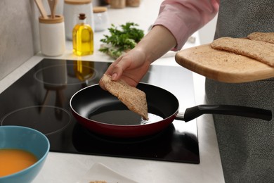 Woman cooking schnitzel in frying pan on stove, closeup