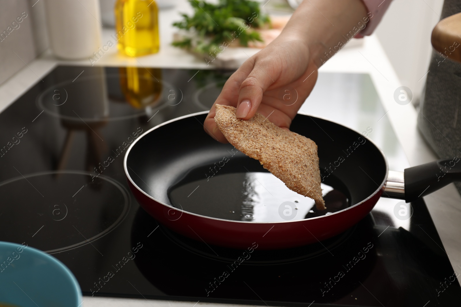 Photo of Woman cooking schnitzel in frying pan on stove, closeup