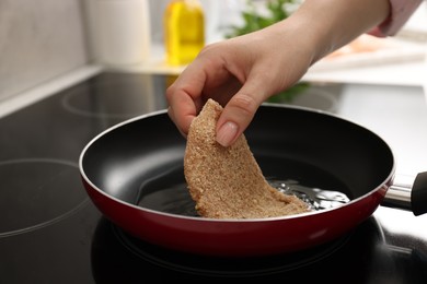 Photo of Woman cooking schnitzel in frying pan on stove, closeup