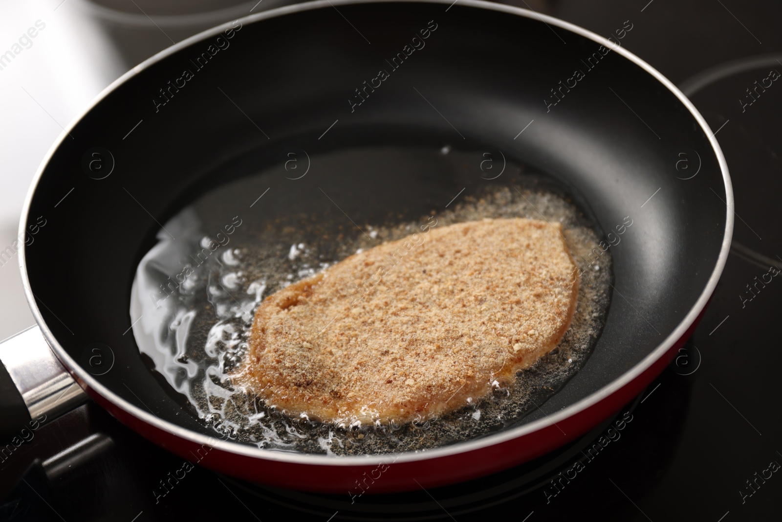 Photo of Cooking schnitzel in frying pan on stove, closeup