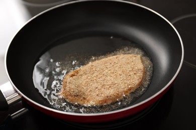 Cooking schnitzel in frying pan on stove, closeup