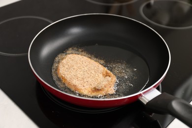 Photo of Cooking schnitzel in frying pan on stove, closeup