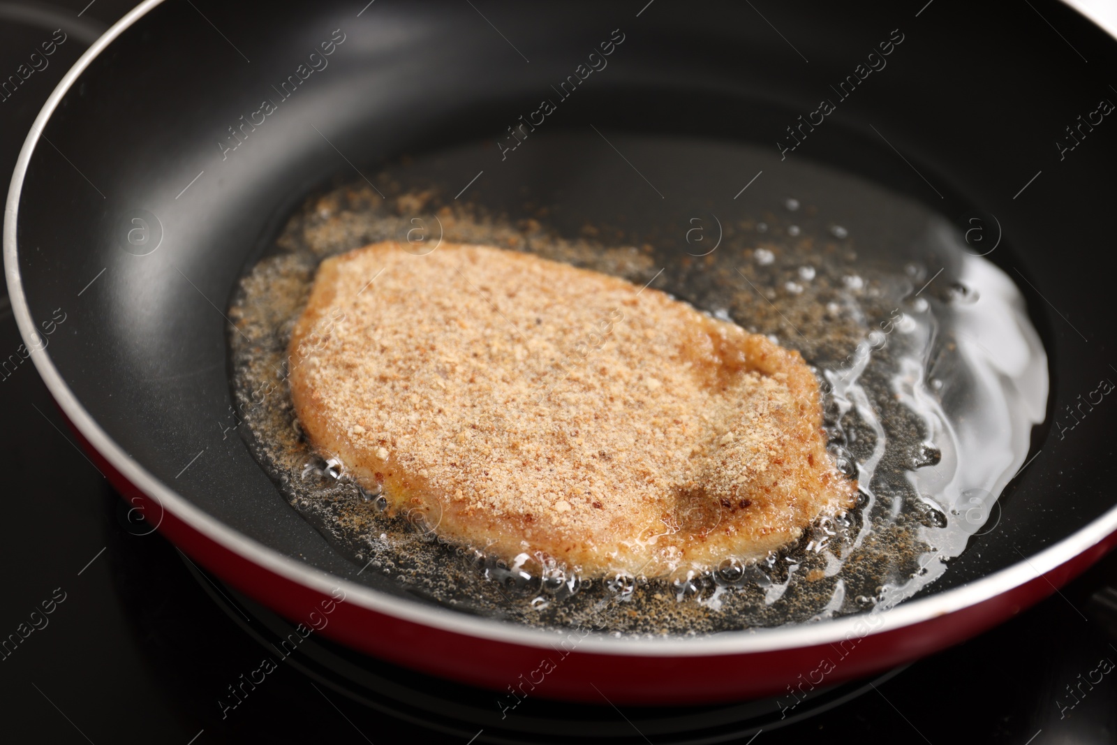 Photo of Cooking schnitzel in frying pan on stove, closeup