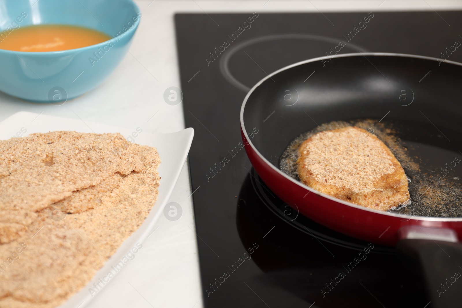 Photo of Cooking schnitzel in frying pan on stove, closeup