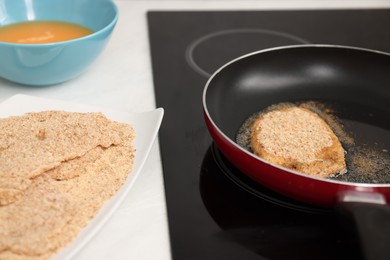 Cooking schnitzel in frying pan on stove, closeup