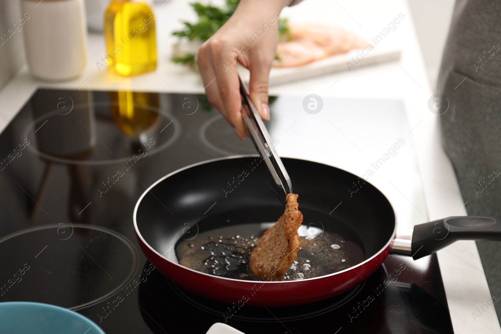 Photo of Woman cooking schnitzel in frying pan on stove, closeup