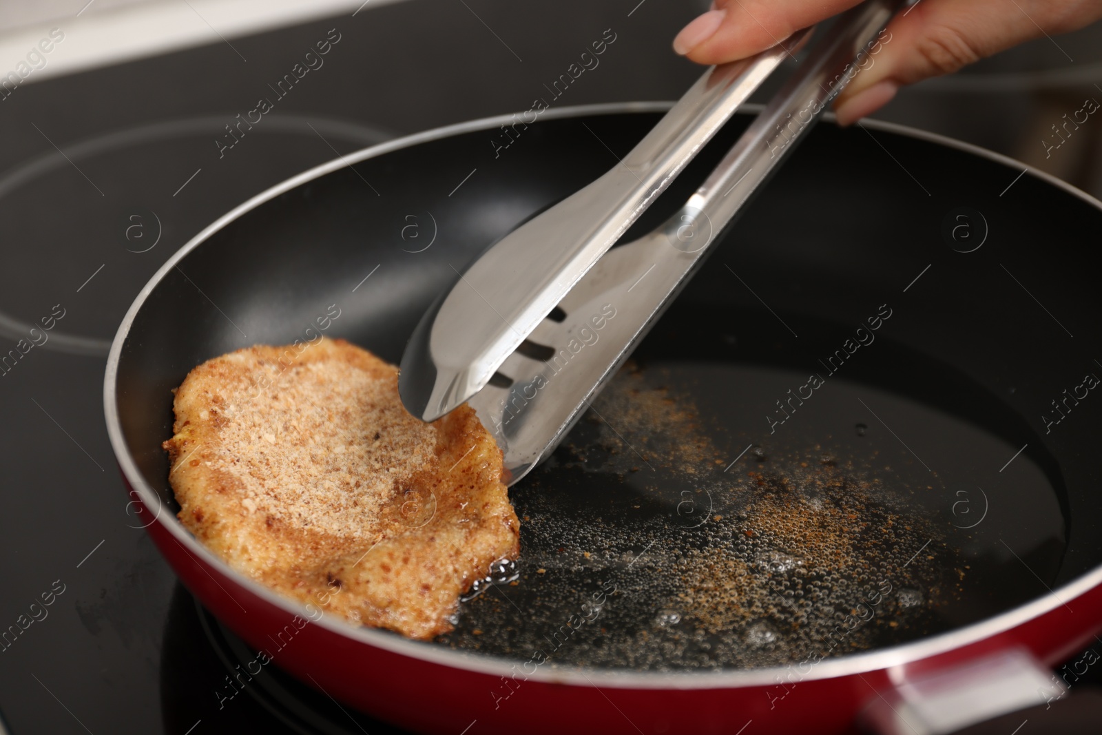 Photo of Woman cooking schnitzel in frying pan on stove, closeup