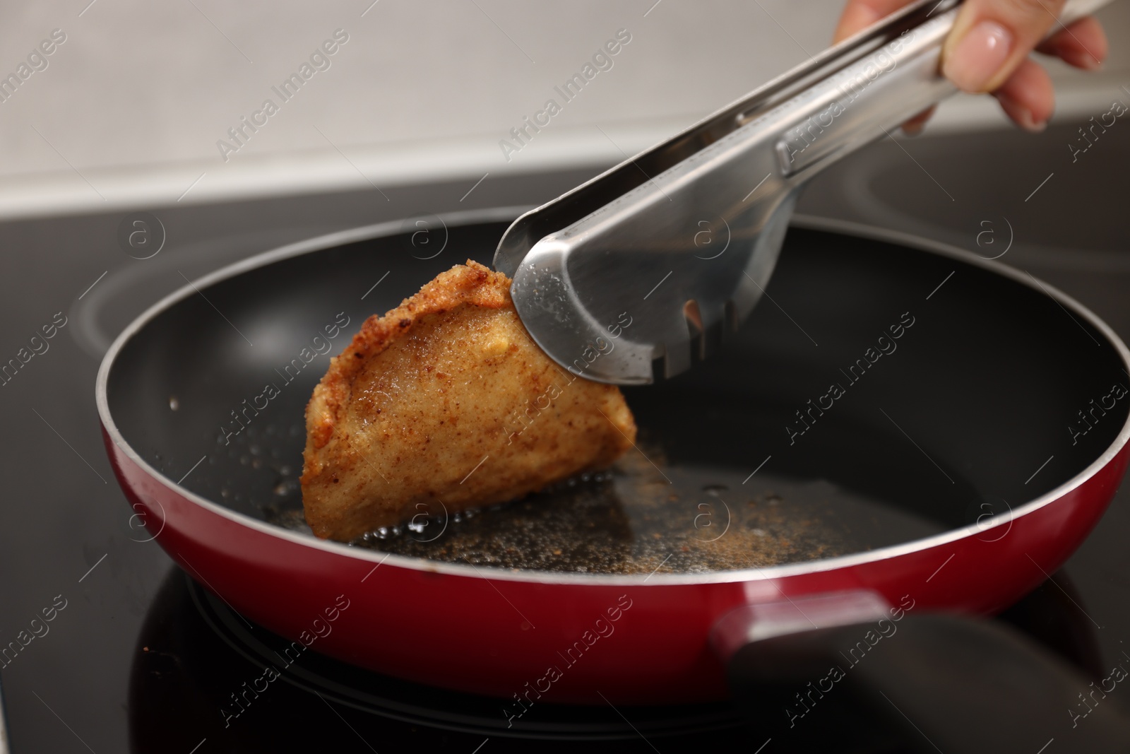 Photo of Woman cooking schnitzel in frying pan on stove, closeup