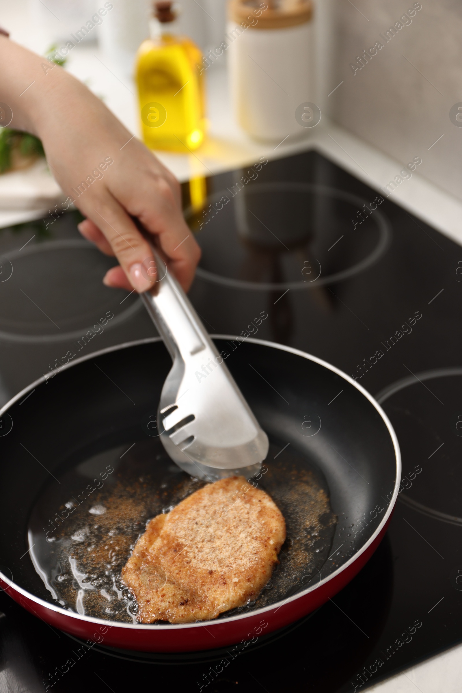 Photo of Woman cooking schnitzel in frying pan on stove, closeup