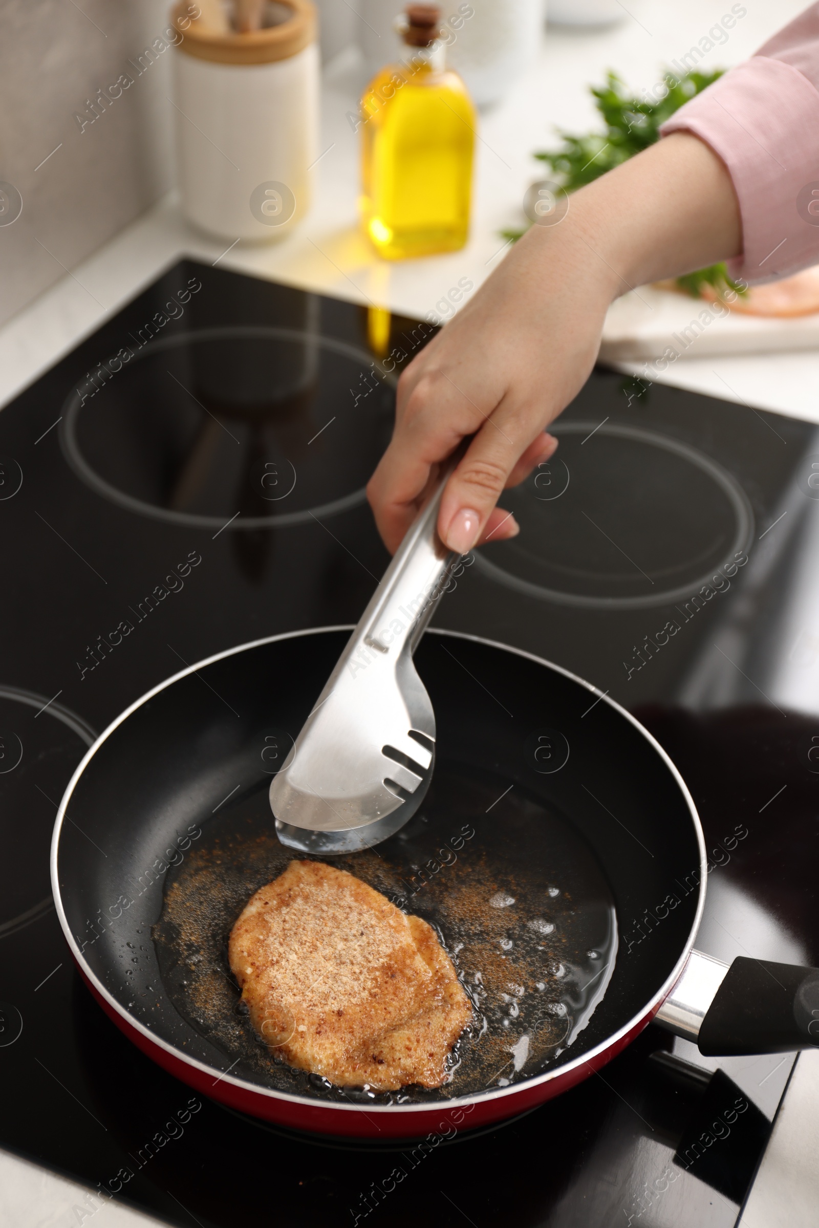 Photo of Woman cooking schnitzel in frying pan on stove, closeup