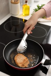 Photo of Woman cooking schnitzel in frying pan on stove, closeup