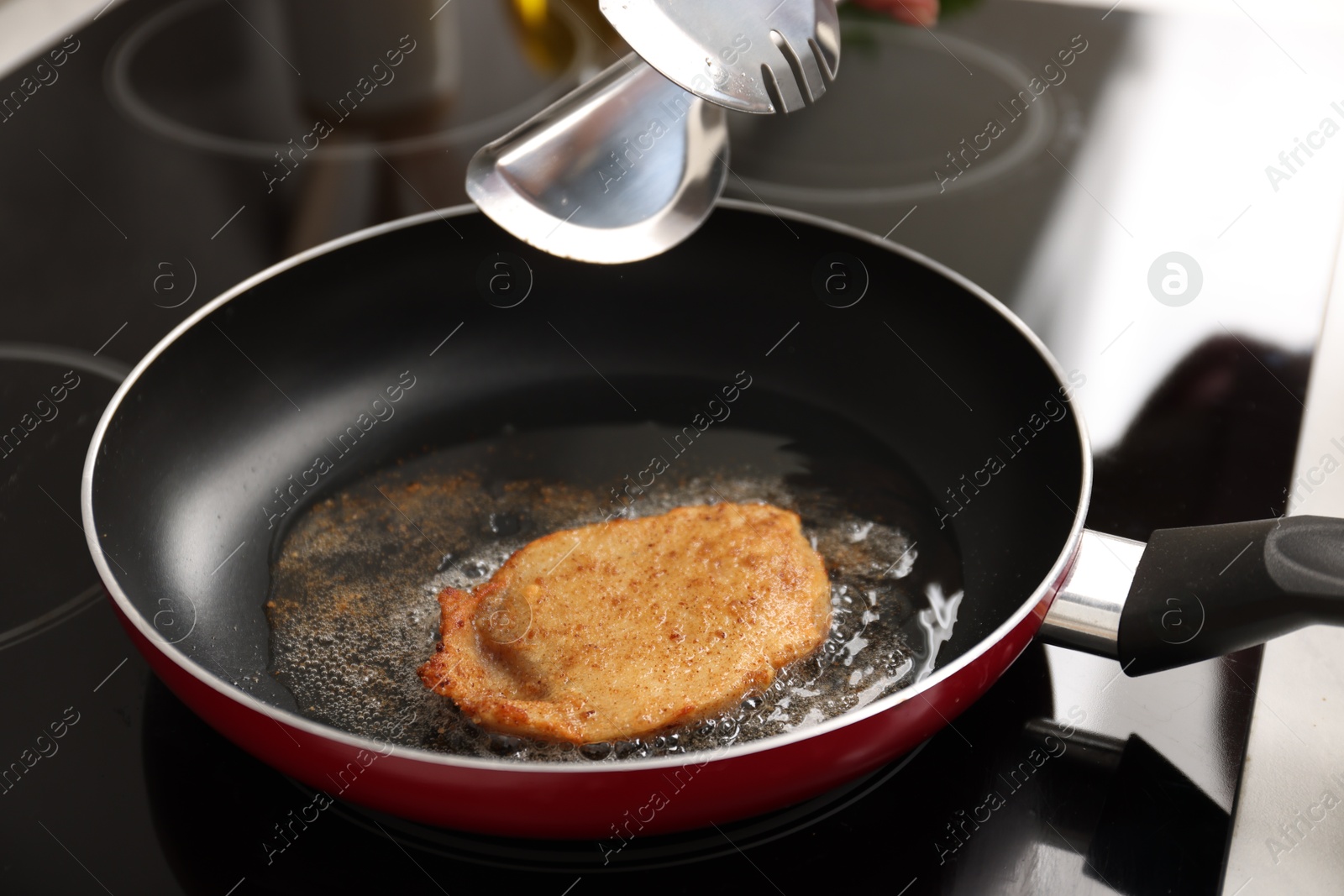 Photo of Cooking schnitzel in frying pan on stove, closeup