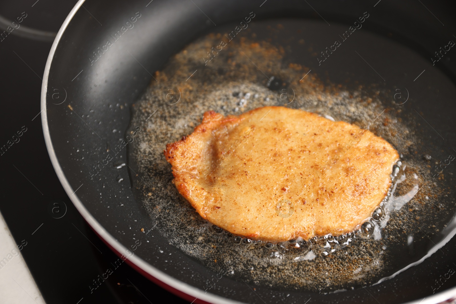 Photo of Cooking schnitzel in frying pan on stove, closeup