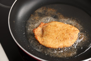 Photo of Cooking schnitzel in frying pan on stove, closeup