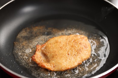 Photo of Cooking schnitzel in frying pan on stove, closeup