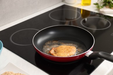 Photo of Cooking schnitzel in frying pan on stove, closeup