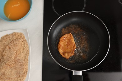 Schnitzel cooking in frying pan on stove, top view