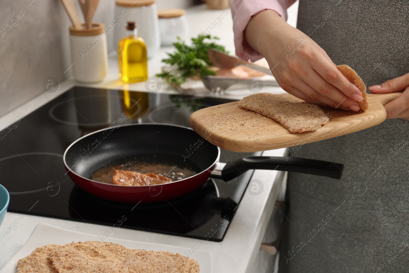 Photo of Woman cooking schnitzel in frying pan on stove, closeup