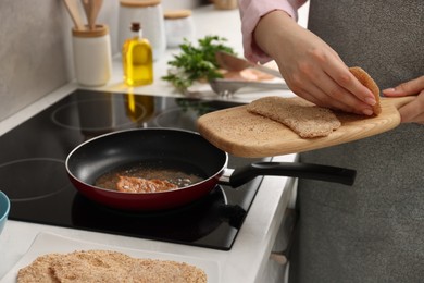 Photo of Woman cooking schnitzel in frying pan on stove, closeup