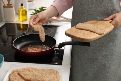 Photo of Woman cooking schnitzel in frying pan on stove, closeup