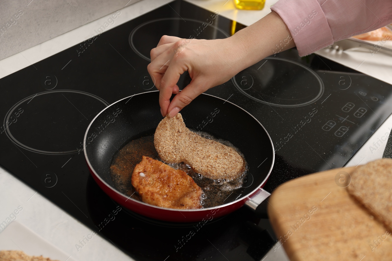 Photo of Woman cooking schnitzels in frying pan on stove, closeup