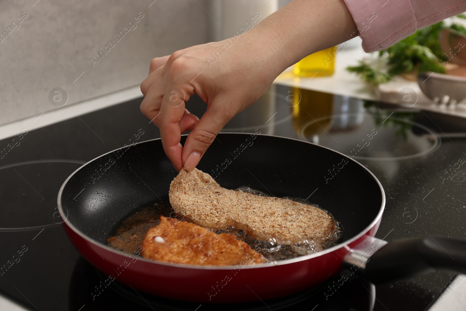 Photo of Woman cooking schnitzels in frying pan on stove, closeup