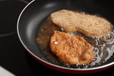 Schnitzels cooking in frying pan on stove, closeup