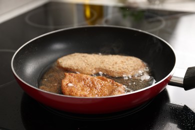 Schnitzels cooking in frying pan on stove, closeup