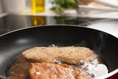 Schnitzels cooking in frying pan on stove, closeup