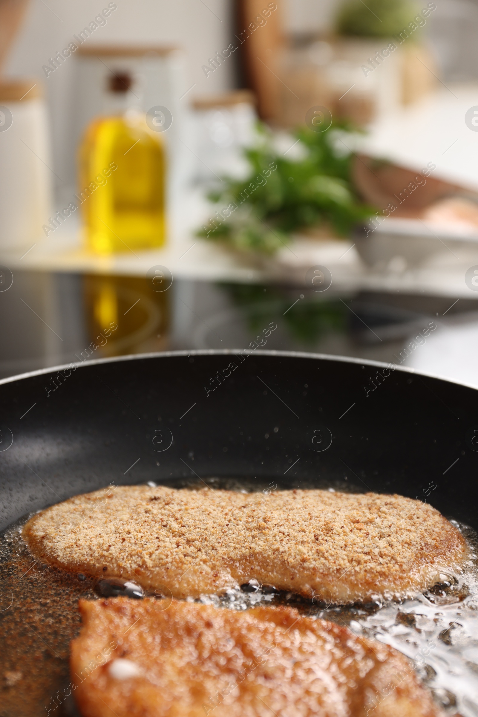 Photo of Schnitzels cooking in frying pan on stove, closeup