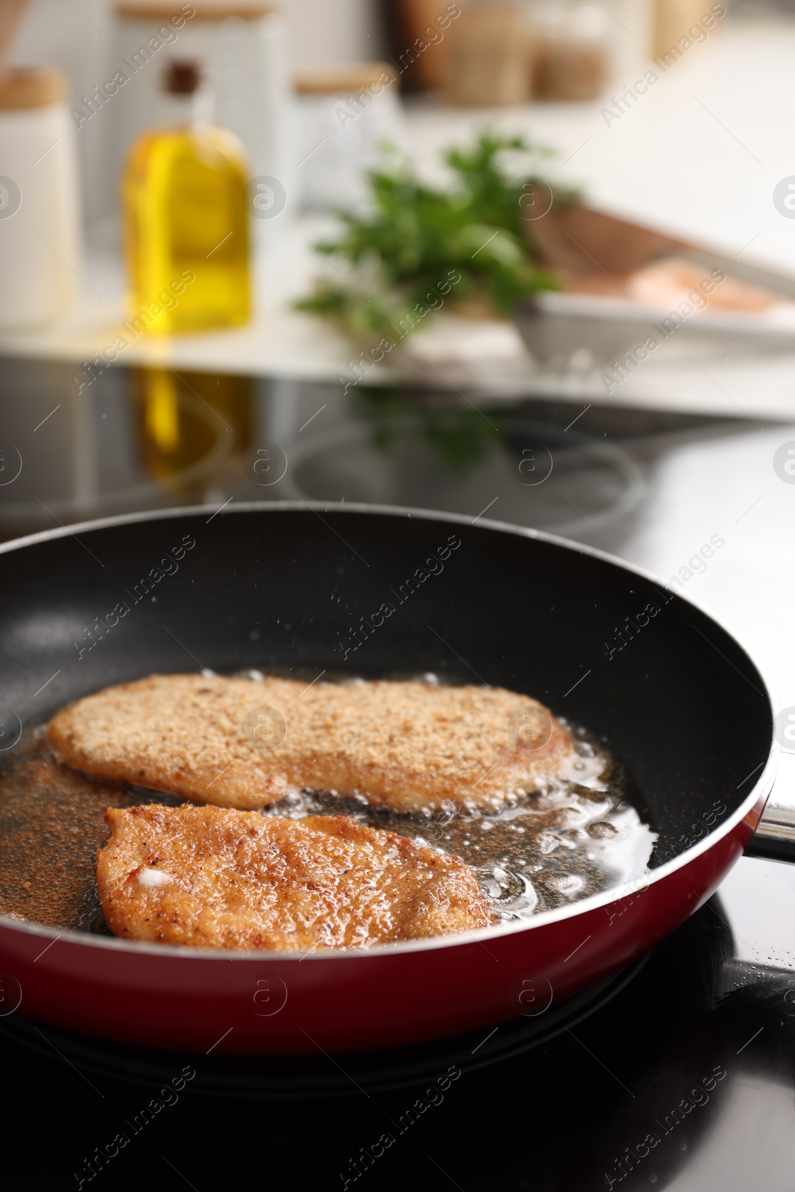 Photo of Schnitzels cooking in frying pan on stove, closeup