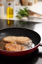 Schnitzels cooking in frying pan on stove, closeup