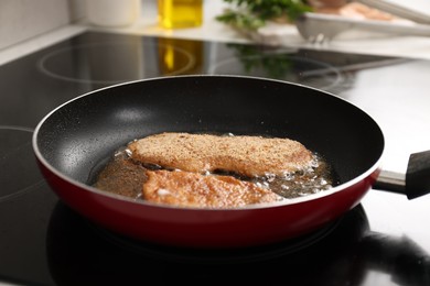 Photo of Schnitzels cooking in frying pan on stove, closeup