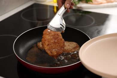 Woman cooking schnitzels in frying pan on stove, closeup