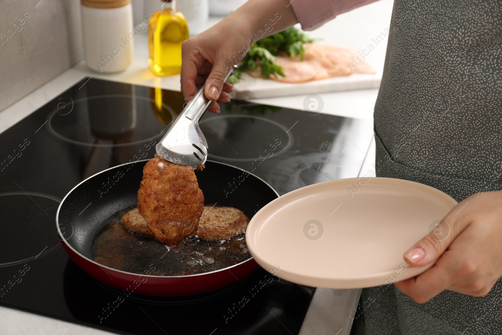 Photo of Woman cooking schnitzels in frying pan on stove, closeup