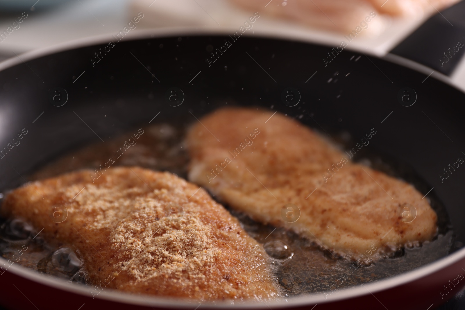 Photo of Schnitzels cooking in frying pan on stove, closeup