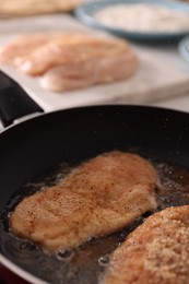 Photo of Schnitzels cooking in frying pan on stove, closeup