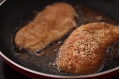 Photo of Schnitzels cooking in frying pan on stove, closeup